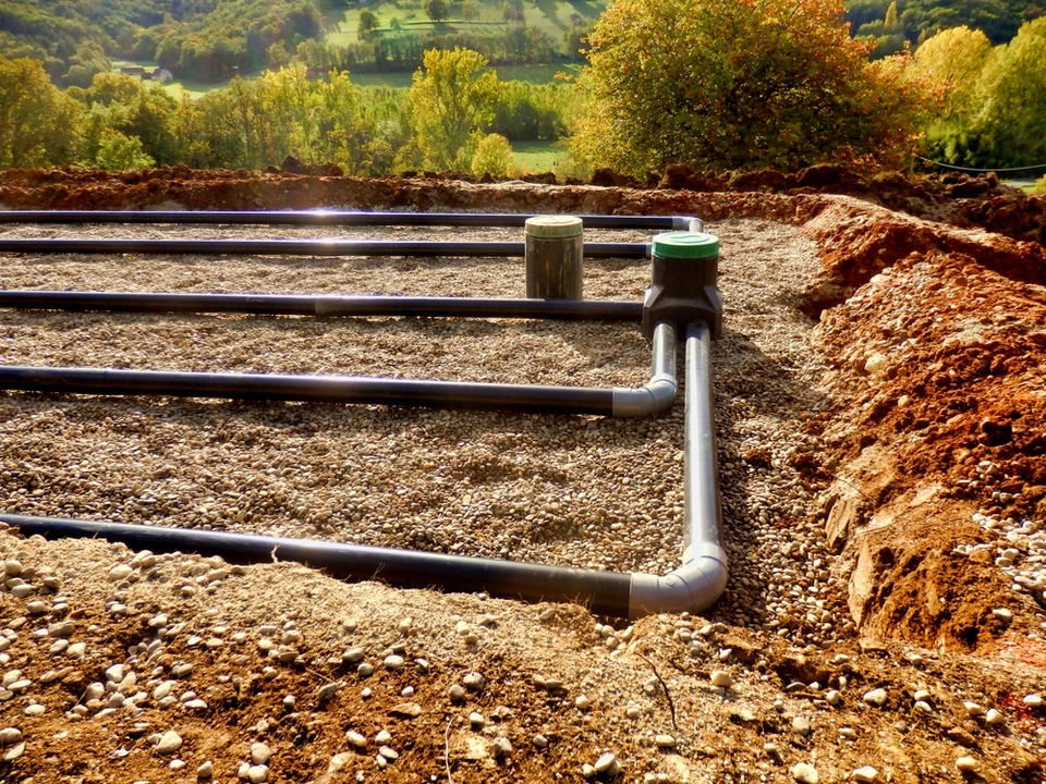 Chantier de construction extérieur avec tranchées d'excavation dans un paysage vallonné aux arbres automnaux